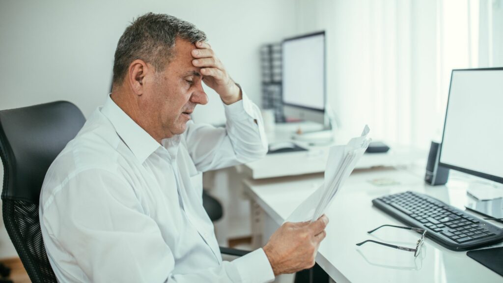 Man looking at marketing papers with hand on head