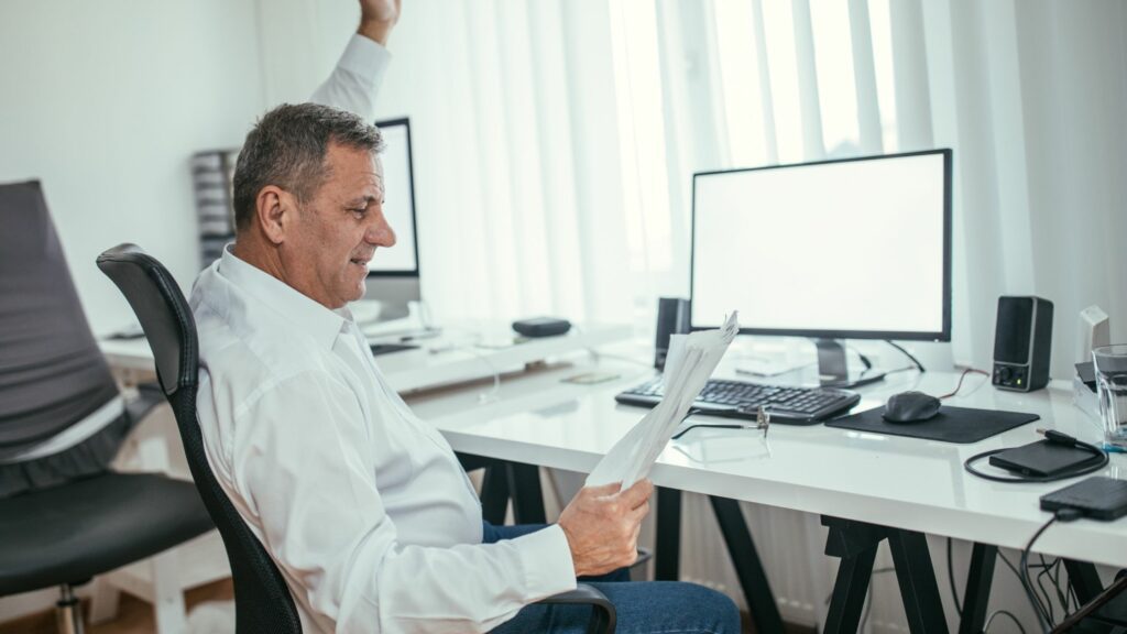 Man at desk with hand in air